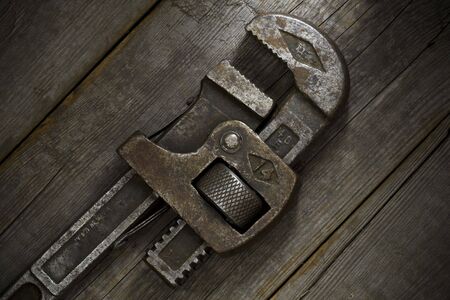 Trusty, old wrench on an old wooden workshop bench.