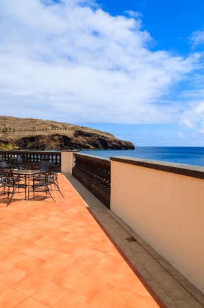 Sea view and metal chairs with glass table on restaurant terrace on sunny summer day , Madeira island, Portugalの写真素材