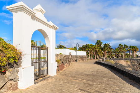 White gate to luxury hotel on coastal promenade in Playa Blanca, Lanzarote island, Spainの写真素材