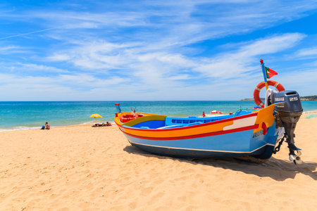 ARMACAO DE PERA BEACH, PORTUGAL - MAY 17, 2015: colorful typical fishing boat on beach in Armacao de Pera coastal village. Algarve region is popular holiday tourist destination on coast of Portugal.のeditorial素材
