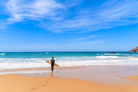 Surfer on Praia do Amado beach on sunny summer day, Algarve region, Portugalの写真素材