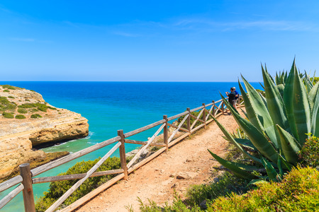 Tourists on cliff path along sea watching beautiful sea bay near Carvoeiro town, Portugalの写真素材