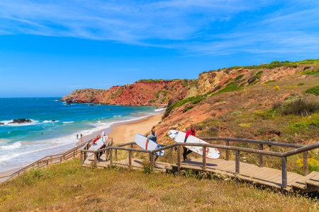 PRAIA DO AMADO BEACH, PORTUGAL - MAY 15, 2015: surfers walking on footbridge from beautiful beach in Algarve region. Surfing is popular sport in south western Portugal due to frequent strong winds.のeditorial素材