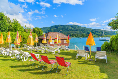 WORTHERSEE LAKE, AUSTRIA - JUN 20, 2015: sunchairs with umbrellas on beach of beautiful alpine lake Worthersee in summer. This iのeditorial素材