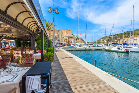 BONIFACIO PORT, CORSICA ISLAND - JUN 23, 2015: restaurant tables in Bonifacio port, most visited tourist attraction on Corsica iのeditorial素材