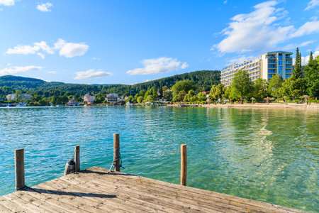 WORTHERSEE LAKE, AUSTRIA - JUN 20, 2015: wooden pier and hotel building along Worthersee lake shore in summer season.のeditorial素材