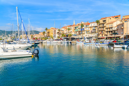 CALVI, CORSICA ISLAND - JUN 29, 2015: sailing and fishing boats in Calvi port with colorful houses in background.のeditorial素材