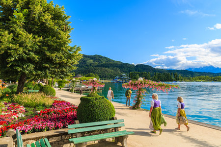 WORTHERSEE LAKE, AUSTRIA - JUN 20, 2015: two women wearing traditional clothes walking along Worthersee lake shore during summerのeditorial素材