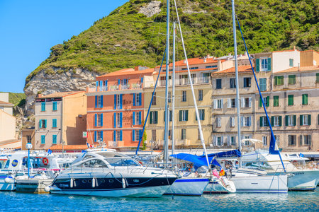 BONIFACIO PORT, CORSICA ISLAND - JUN 24, 2015: boats anchoring in Bonifacio port with colorful houses in background.のeditorial素材