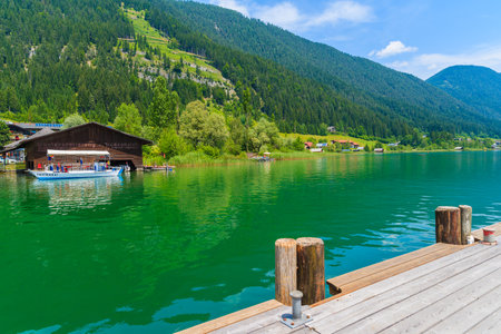 WEISSENSEE LAKE, AUSTRIA - JUL 6, 2015: wooden jetty in alpine village on shore of Weissensee lakeのeditorial素材