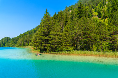 WEISSENSEE LAKE, AUSTRIA - JUL 7, 2015: couple of people in small boat on crystal clear water of Weissensee lake in Alps Mountainのeditorial素材