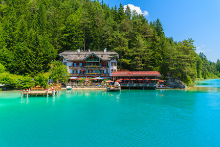 WEISSENSEE LAKE, AUSTRIA - JUL 7, 2015: restaurant and guest house on shore of Weissensee lake in summer time.のeditorial素材