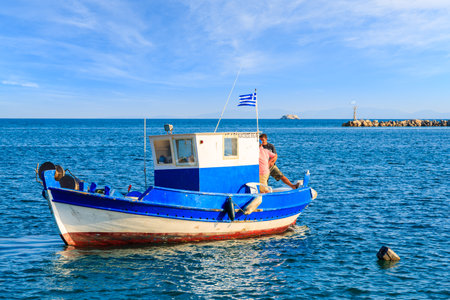 SAMOS ISLAND, GREECE - SEP 20, 2015: Greek fishing boat on blue sea with two fishermen on board, Samos island, Greece.のeditorial素材