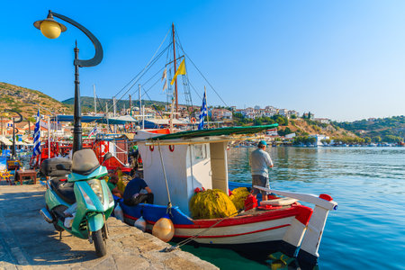 PYTHAGORION PORT, SAMOS ISLAND - SEP 19, 2015: fisherman standing on a boat in beautiful Pythagorion port on Samos island, Greeceのeditorial素材