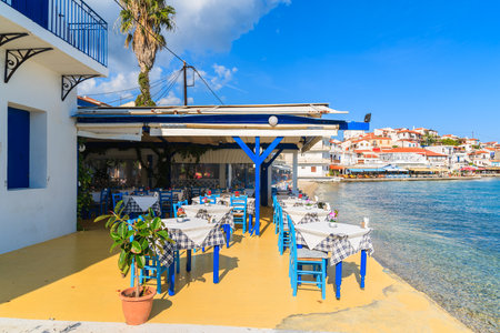 KOKKARI, SAMOS ISLAND - SEP 25, 2015: Tables with chairs in traditional Greek tavern in Kokkari town on coast of Samos island, Greeceのeditorial素材