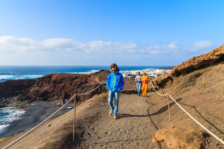 EL GOLFO, LANZAROTE ISLAND - JAN 15, 2015: tourists on trekking path from Lago Verde lake to El Golfo village, Lanzarote, Canary Islands, Spainのeditorial素材