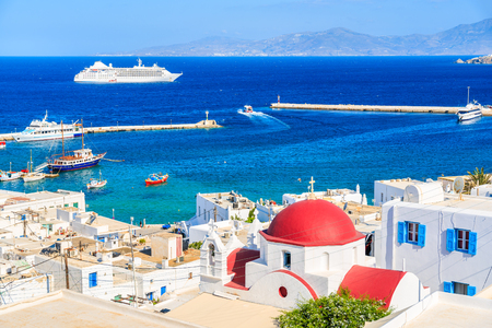 Typical Greek white church with red dome and view of Mykonos port, Mykonos island, Cyclades, Greeceの写真素材