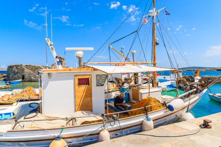 NAOUSSA PORT, PAROS ISLAND - MAY 18, 2016: fisherman working on a boat in Naoussa port on sunny day, Paros island, Cyclades, Greece.のeditorial素材