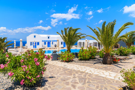 OIA VILLAGE, SANTORINI ISLAND - MAY 23, 2016: Typical Greek style holiday apartments in a beautiful garden with palm trees in Oia village on Santorini island, Greece.のeditorial素材