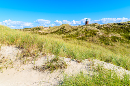Lighthouse on sand dune against blue sky with white clouds on northern coast of Sylt island near Kampen village, Germanyの写真素材
