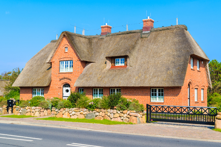 SYLT ISLAND, GERMANY - SEP 7, 2016: typical red brick house with thatched roof on street of Kampen village on Sylt island, Germany.の写真素材
