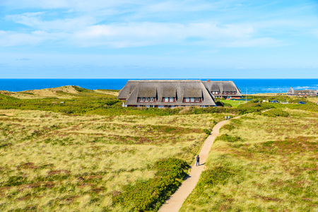 Tourist walking on countryside path in Kampen village on western coast of Sylt island, Germanyの写真素材