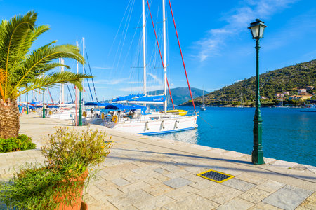 AGIA EFIMIA PORT, KEFALONIA ISLAND, GREECE - SEP 17, 2014: Promenade in Agia Efimia village with yacht boats mooring in marina. Yachting is a popular sport and leisure activity in Greek islands.のeditorial素材