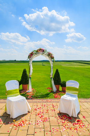 Arch and two white chairs in golf club prepared for weeding ceremony, Polandの写真素材