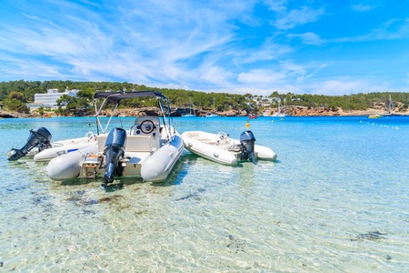 Dinghy motor boats in water on Cala Portinatx beach, Ibiza island, Spainの写真素材