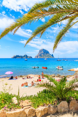 IBIZA ISLAND, SPAIN - MAY 18, 2017: View of idyllic beach of Cala d'Hort wih palm tree leaves in foreground, Ibiza island, Spain.のeditorial素材