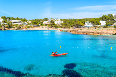 CALA PORTINATX BAY, IBIZA ISLAND - MAY 22, 2017: Tourists in kayak paddling on blue sea water of Cala Portinatx bay, Ibiza island, Spain.のeditorial素材