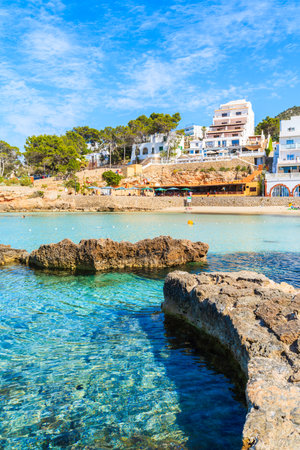 Hotel and restaurant buildings in Cala Portinatx bay with azure blue sea water, Ibiza island, Spainのeditorial素材
