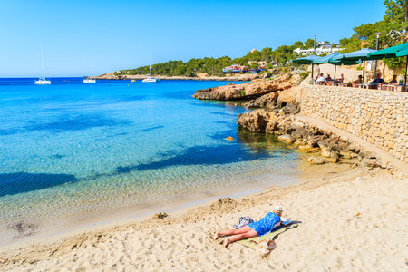 CALA PORTINATX, IBIZA ISLAND - MAY 22, 2017: woman laying on beach and reading book in Cala Portinatx bay on Ibiza island, Spain.のeditorial素材