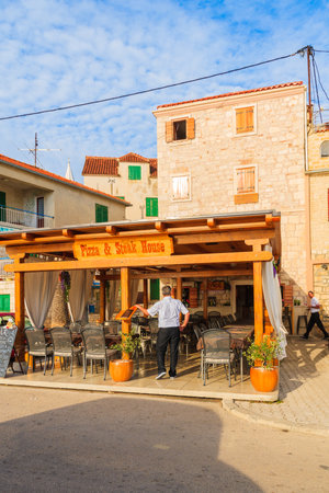 ROGOZNICA PORT, CROATIA - SEP 5, 2017: Waiter standing in traditional restaurant in Rogoznica old town on sunny summer day, Dalmatia, Croatia.のeditorial素材