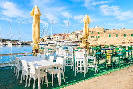 PRIMOSTEN PORT, CROATIA - SEP 5, 2017: White tables with chairs of traditional restaurant in Primosten port at early morning time, Dalmatia, Croatiaのeditorial素材