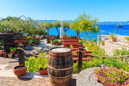 BOL TOWN, BRAC ISLAND - SEP 14, 2017: Traditional restaurant decorated with flowers and wine barrels with sea view in Bol town, Brac island, Croatia.のeditorial素材
