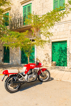 SUMARTIN TOWN, CROATIA - SEP 13, 2017: Red motorcycle parking in front of a typical house in Sumartin town, Brac island, Croatia.のeditorial素材