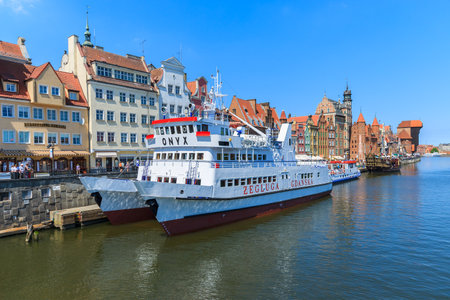 GDANSK, POLAND - JUN 9, 2013: Tourist ship and colourful historic houses by Motlawa river in port of...