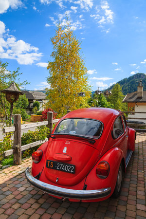 COLFOSCO, ITALY - SEP 26, 2013: Vintage red Volkswagen VW Beetle car parked in front of a house in alpine village Colfosco, Dolomites Mountains, Italy.のeditorial素材
