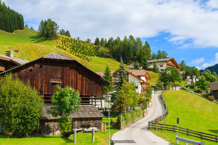 COLFOSCO, ITALY - SEP 26, 2013: Traditional houses along a street in alpine village on sunny day, Colfosco, The Dolomites Mountains. Northern Italy is known for idyllic mountain villages.のeditorial素材