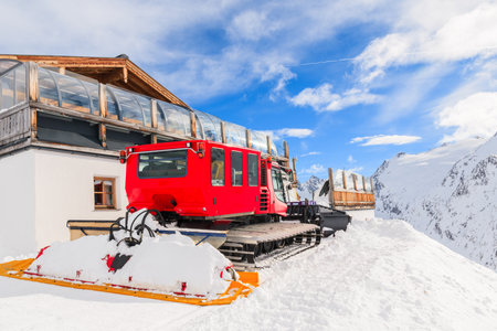 Red piste groomer parking in front of wooden mountain hut on slope in Hochgurgl-Obergurgl ski area on beautiful sunny day, Tirol, Austriaのeditorial素材