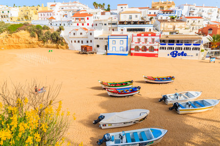 CARVOEIRO BEACH, PORTUGAL - MAY 12, 2015: Fishing boats on beach in Carvoeiro village with colorful houses. Algarve region is popular holiday destination due to sunny climate.のeditorial素材