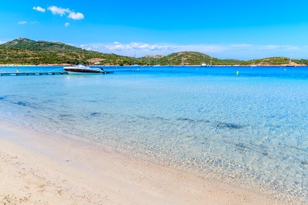 Boat on crystal clear azure sea water of Santa Giulia beach, Corsica island, France