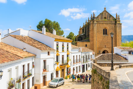 RONDA TOWN, SPAIN - MAY 10, 2018: Street with white houses and castle cathedral in Andalusian village of Ronda. This place is one of most visited by tourists destinations in southern Spain.のeditorial素材
