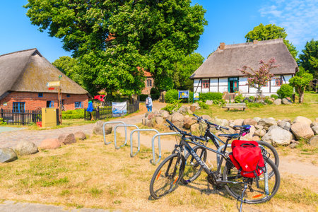 MIDDELHAGEN VILLAGE, RUEGEN ISLAND - MAY 31, 2018: Bicycle parking in Middelhagen village with traditional straw roof houses, Baltic Sea, Germany. Rugen is popular destination for cyclists in summer.のeditorial素材