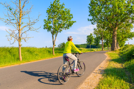 BAABE, RUEGEN ISLAND - MAY 31, 2018: Young woman cyclist riding bicycle on route from Seedorf to Baabe village in countryside spring landscape, Ruegen island, Baltic Sea, Germany.のeditorial素材