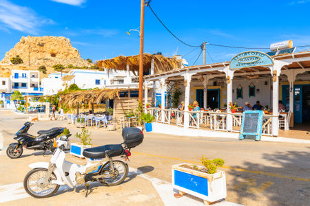 FINIKI PORT, KARPATHOS ISLAND - SEP 30, 2018: Scooters parking in front of typical Greek tavern on street of Finiki port, Karpathos island, Greece.のeditorial素材
