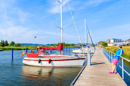 MORITZDORF, RUGEN ISLAND - MAY 28, 2018: Young woman tourist standing on pier in sailing marina in Moritzdorf village on coast of Rugen island, Baltic Sea, Germany.のeditorial素材