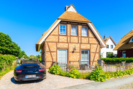 GROSS ZICKER VILLAGE, RUGEN ISLAND - MAY 29, 2018: Traditional house with thatched roof and luxury car on driveway in Gross Zicker village. Rugen island is popular holiday destination in summer.のeditorial素材