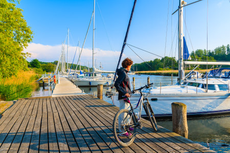 SEEDORF PORT, RUGEN ISLAND - MAY 27, 2018: Woman with bicycle standing in beautiful marina on coast of Rugen island, Baltic Sea, Germany. It is very popular cycling destination in summer season.のeditorial素材